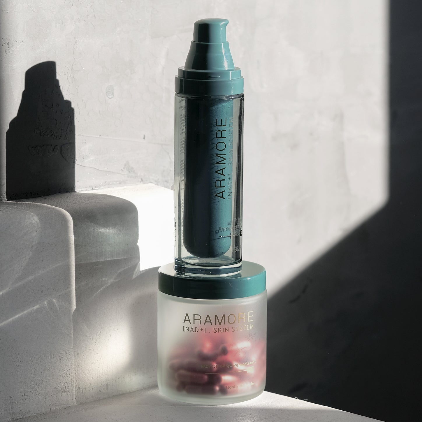 Two Aramore skincare bottles with sleek, minimalistic design on a textured surface.