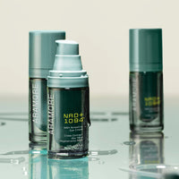 Three NAD+ Renewing Eye Cream bottles styled on a mirrored table with water droplets falling off bottles 