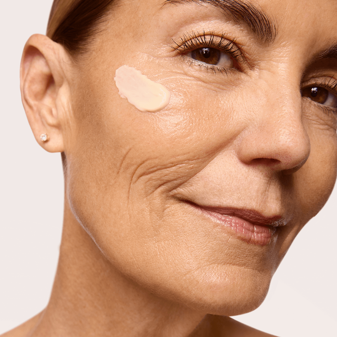 Close-up of a woman's face with a dab of Restoration Cream applied to her cheek.