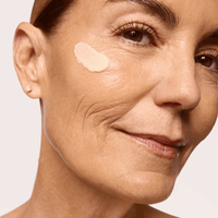 Close-up of a woman's face with a dab of Restoration Cream applied to her cheek.
